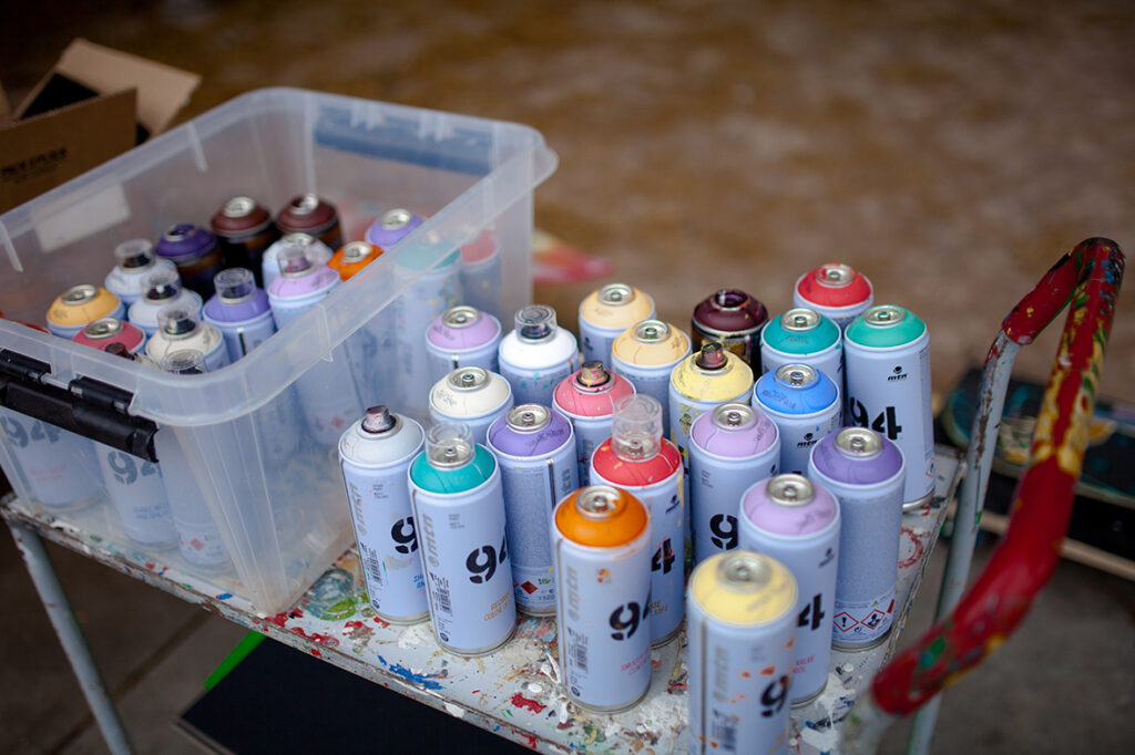 Sprayfärger i glada och pastelliga färger står på en vagn.