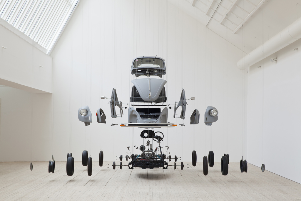 A disassembled Volkswagen hangs in the art gallery.
