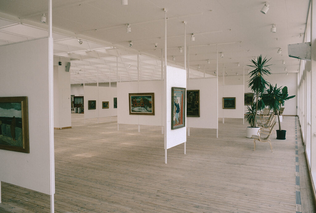 Målningar, klassiskt upphängda på rad i konsthallsrummet.