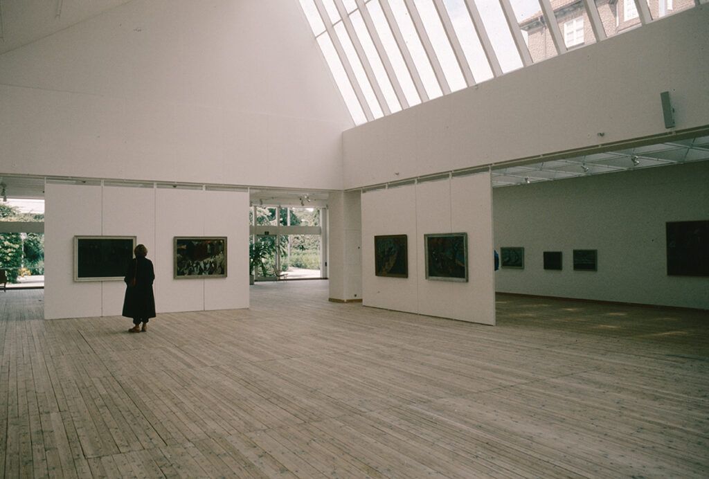 Målningar, klassiskt upphängda på rad i konsthallsrummet.