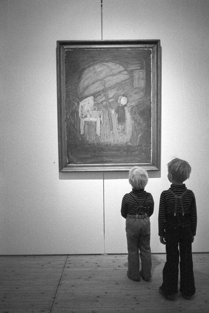 Två barn står framför en målning som är upphängd på väggen.