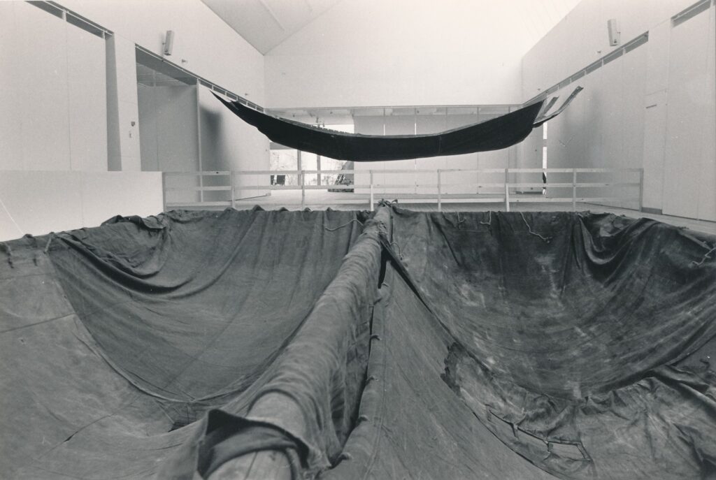 Installation bestående av en stor presenning uppspänd i taket och hänger ned i konsthallens ljusschakt.