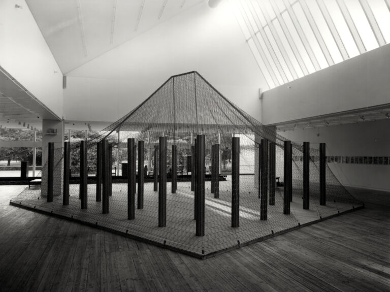 Konstinstallation bestående av ett nätliknande material uppspänt mellan metallpelare i en konsthall.