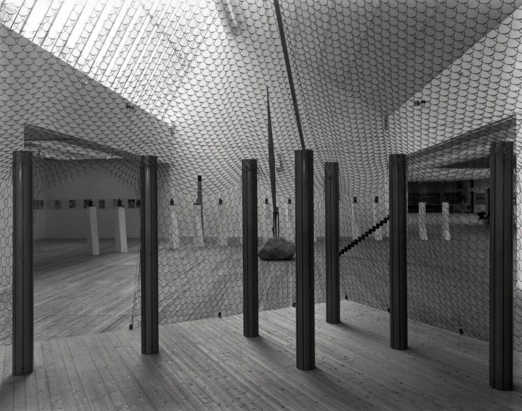 Konstinstallation bestående av ett nätliknande material uppspänt mellan metallpelare i en konsthall.