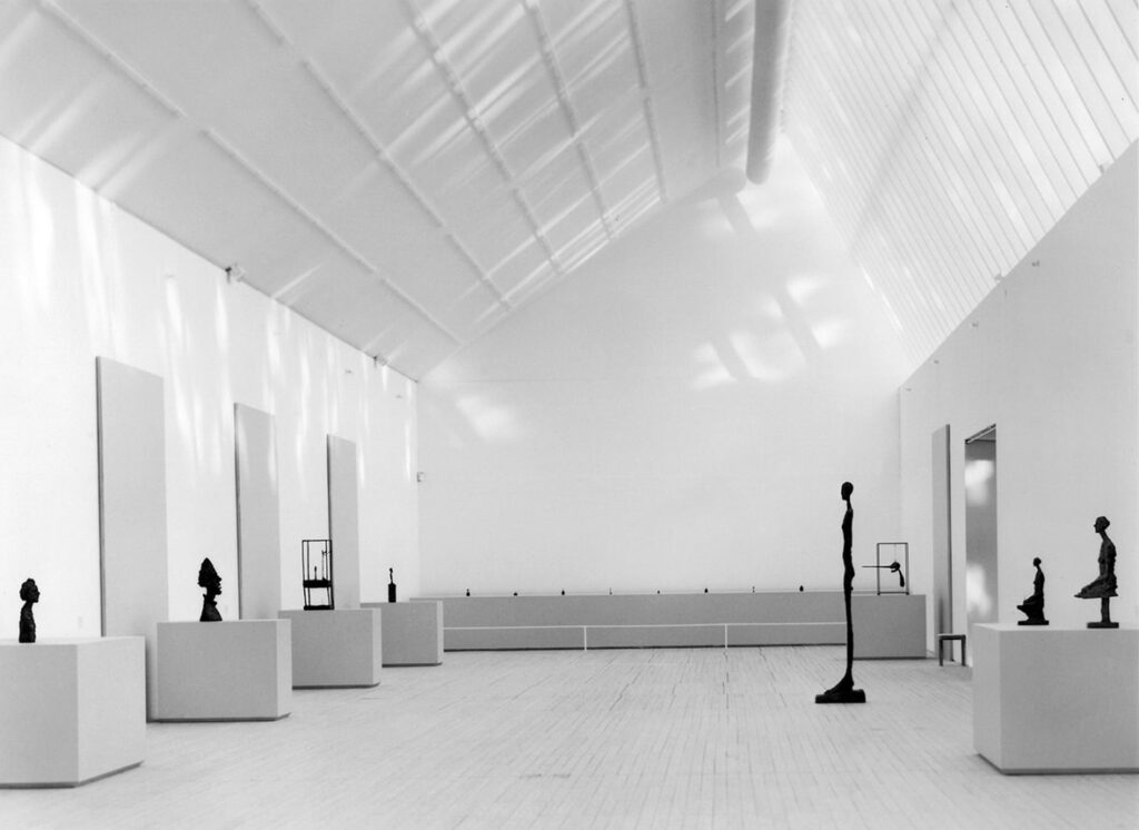Översiktsbild av Malmö Konsthall. Längst med väggarna står skulpturer av Alberto Giacometti på piedestaler.
