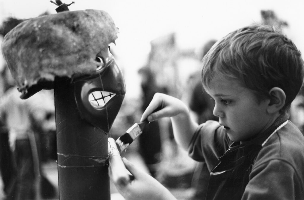 En pojke målar en pinne som hänger på en skulptur.
