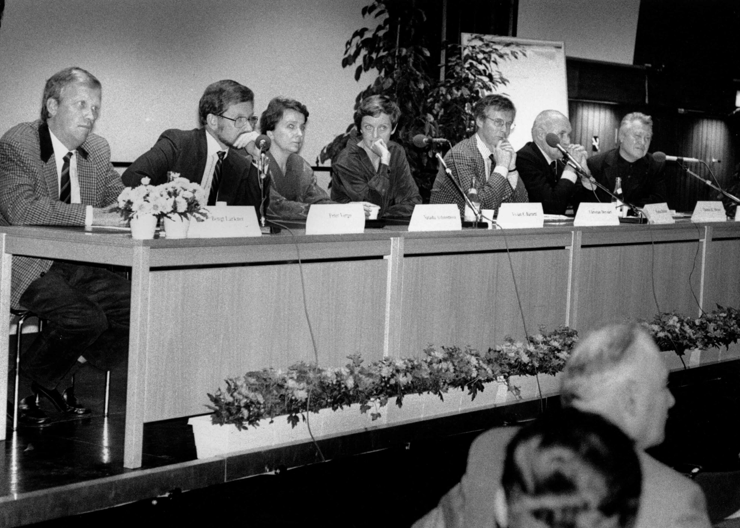 Svartvitt fotografi av sju personer som sitter vid ett långt jury-bord.
