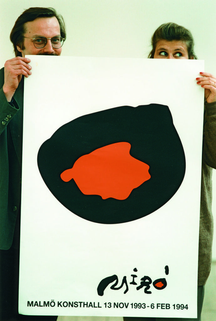 Två personer håller upp en affisch av Joan Miró.