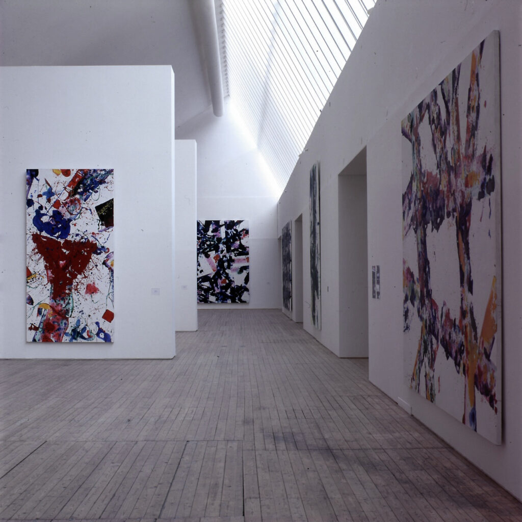 Färgstarka målningar av Sam Francis, upphängda på väggar i en konsthall med ljusa väggar och trägolv.