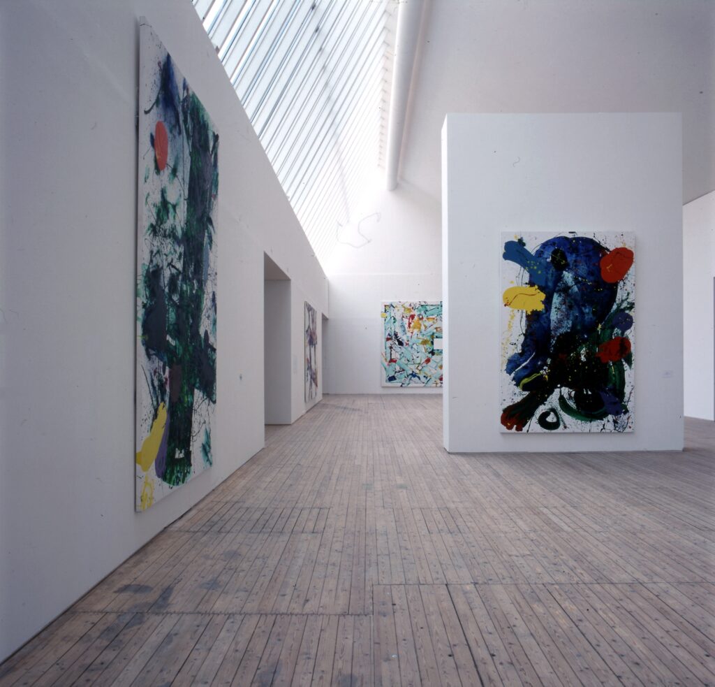 Färgstarka målningar av Sam Francis, upphängda på väggar i en konsthall med ljusa väggar och trägolv.