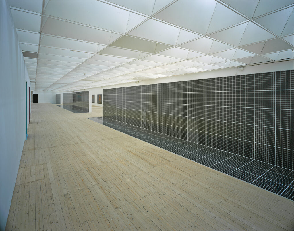 Verk av Magnus Vallin. Lång, uppbruten skärmvägg klädd med ett svartvitt rutnät.