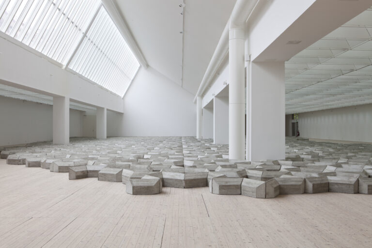 En installation av Mike Nelson i form av ett betongverk breder ut sig över konsthallens golv.