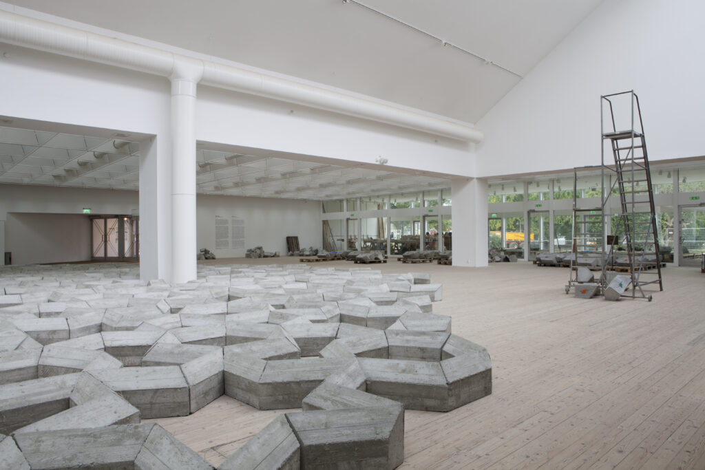 Installation av Mike Nelson i form av ett betongverk breder ut sig över golvet i konsthallen.