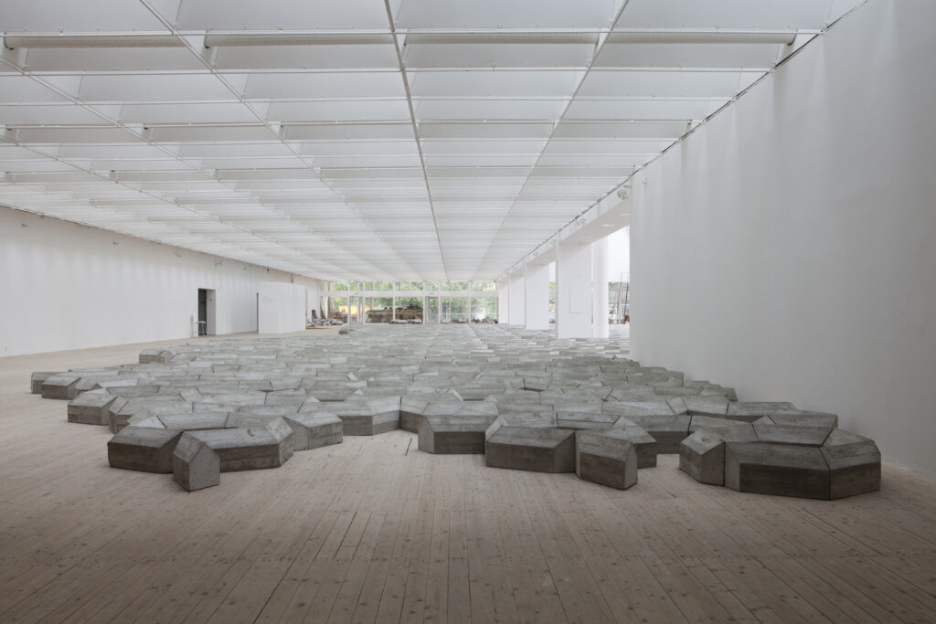 Ett betongverk av Mike Nelson breder ut sig över golvet i konsthallen.