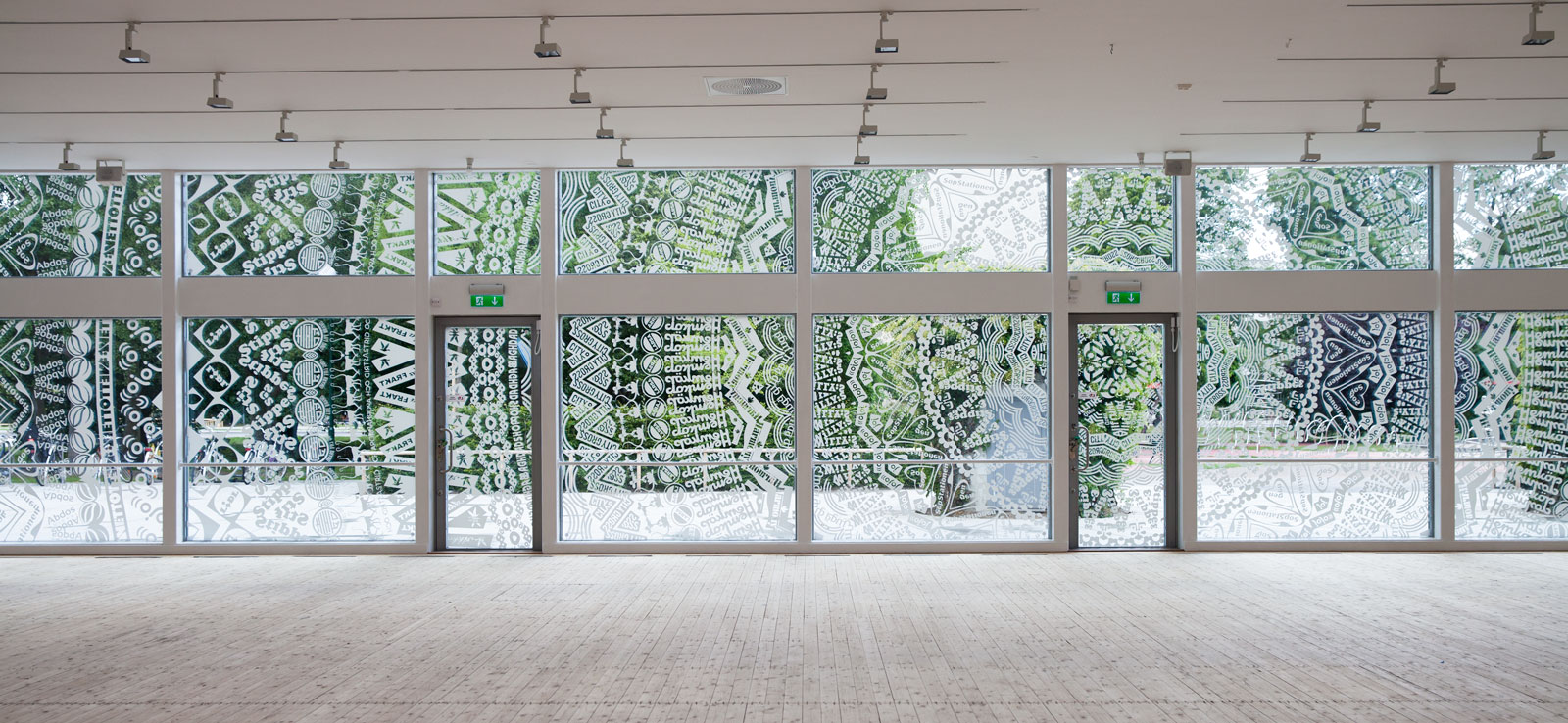 Installationsbild av Gunilla Klingbergs utställning på Malmö Konsthall 2014. Konsthallens fönster ut mot Magistratsparken har beklätts med ett transparent mönster uppbyggt av olika logotyper från varumärken/butiker i staden.