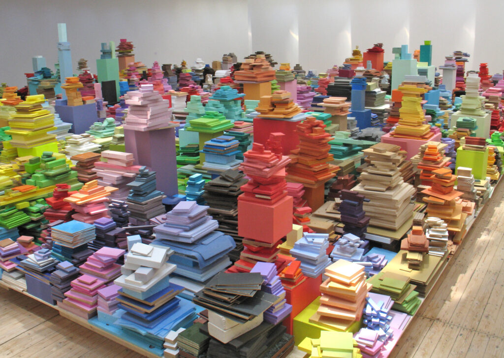 Ett rum fyllt med staplade högar med färgstarka träplattor.