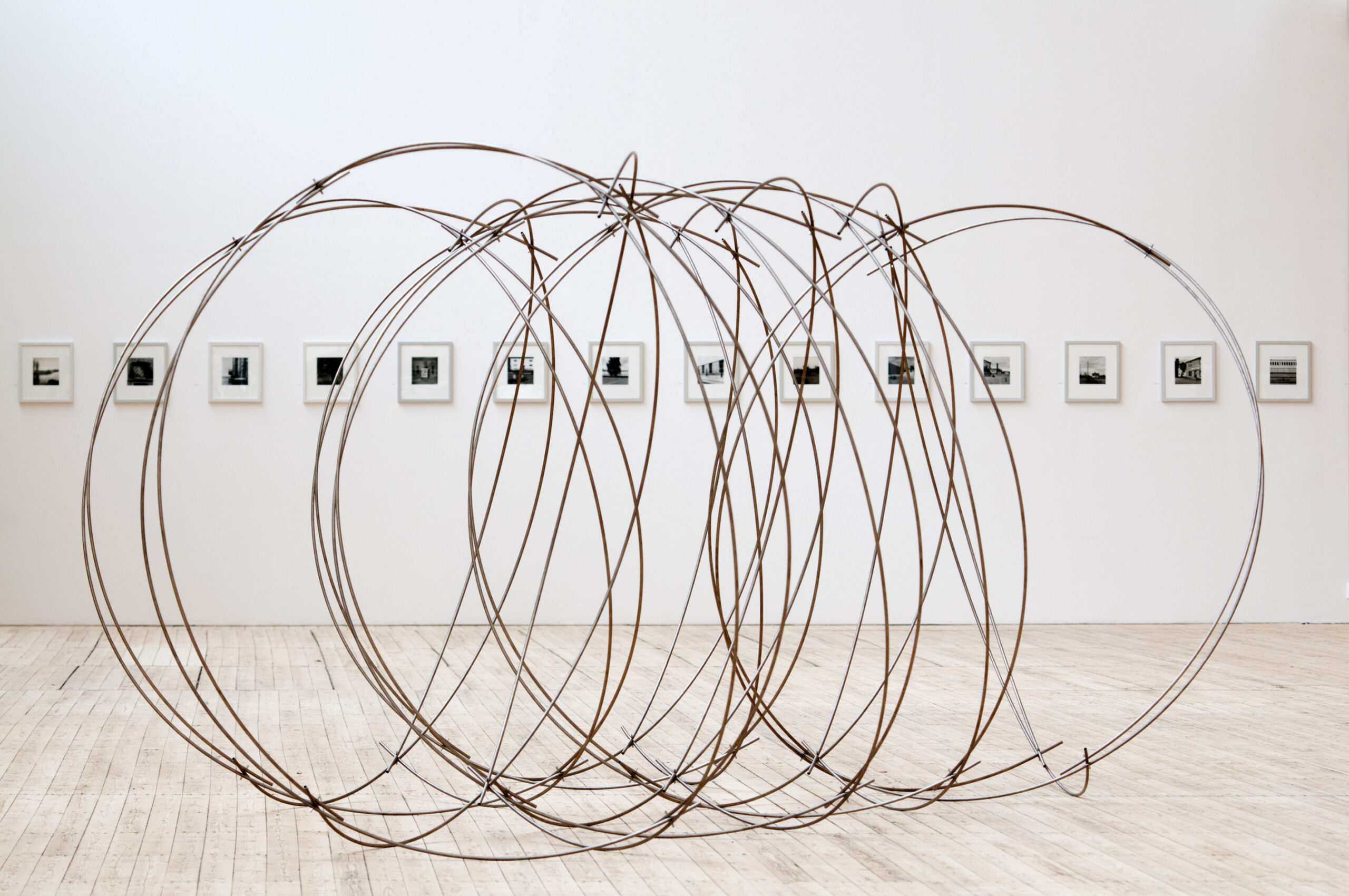 Lars Englunds stora spiralkonstruktion i utställningshallen, bakom den skymtar man Gerry Johanssons fotografier på rad.