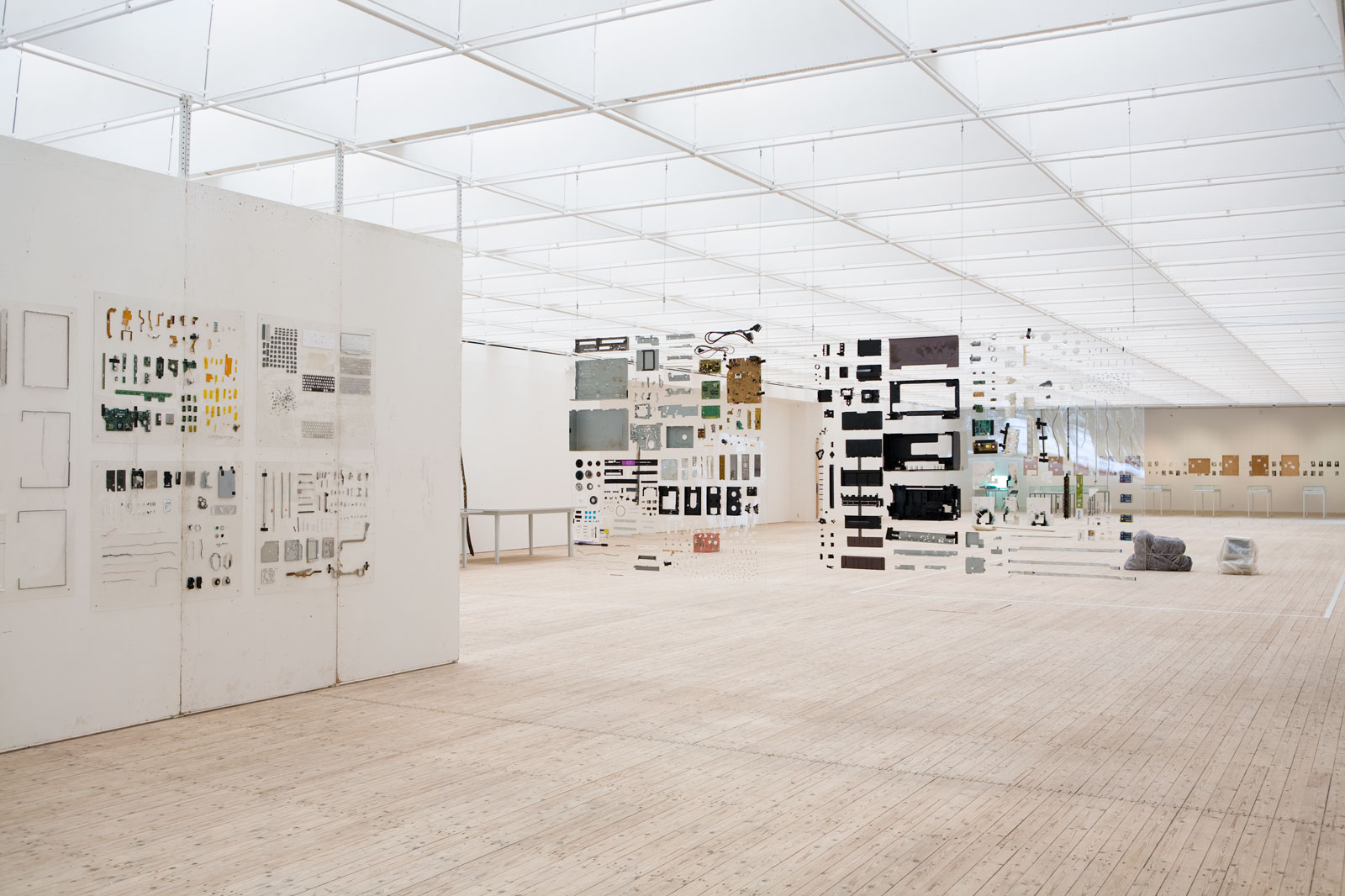Installationsbild/vy av Henrik Olesens utställning på Malmö Konsthall 2014. Sönderskruvade apparater av olika slag hänger i skulpturala former av grafiska mönster runt om i utställningsrummet.