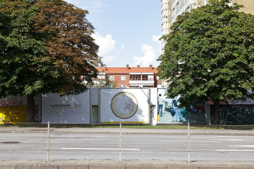 Tre billboard-tavlor syns på andra sidan vägen. Det står två stora träd på vardera sida.