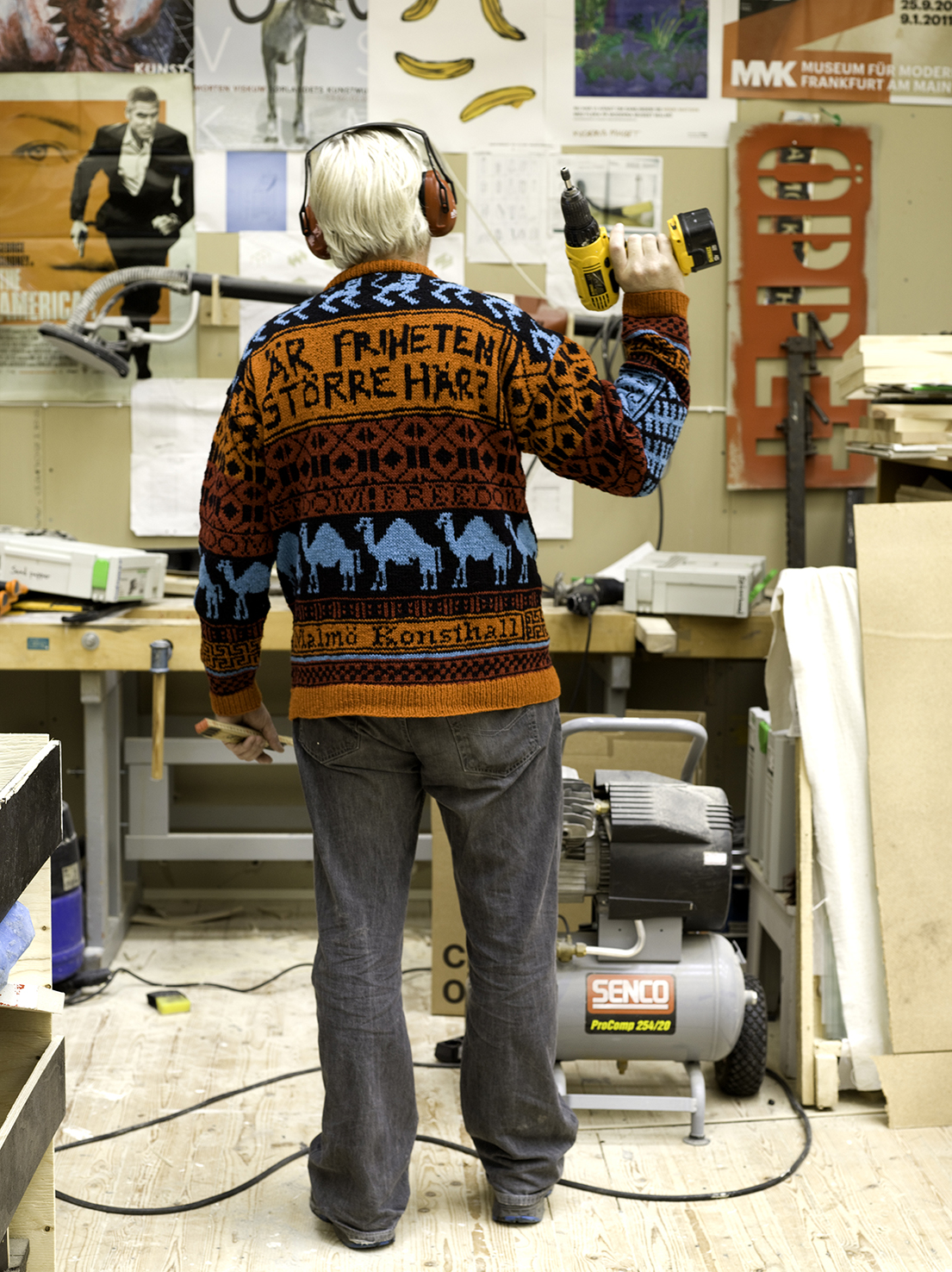 Bild från Malmö Konsthalls träverkstad, en i personalen bär en tröja stickad av konstnären Lisa Ann Auerbach