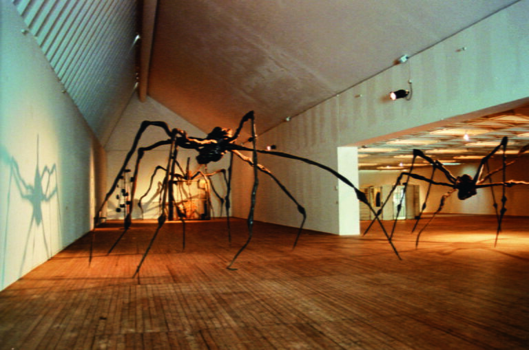 Översiktsbild över tre stora, spindelliknande skulpturer som står i konsthallen.