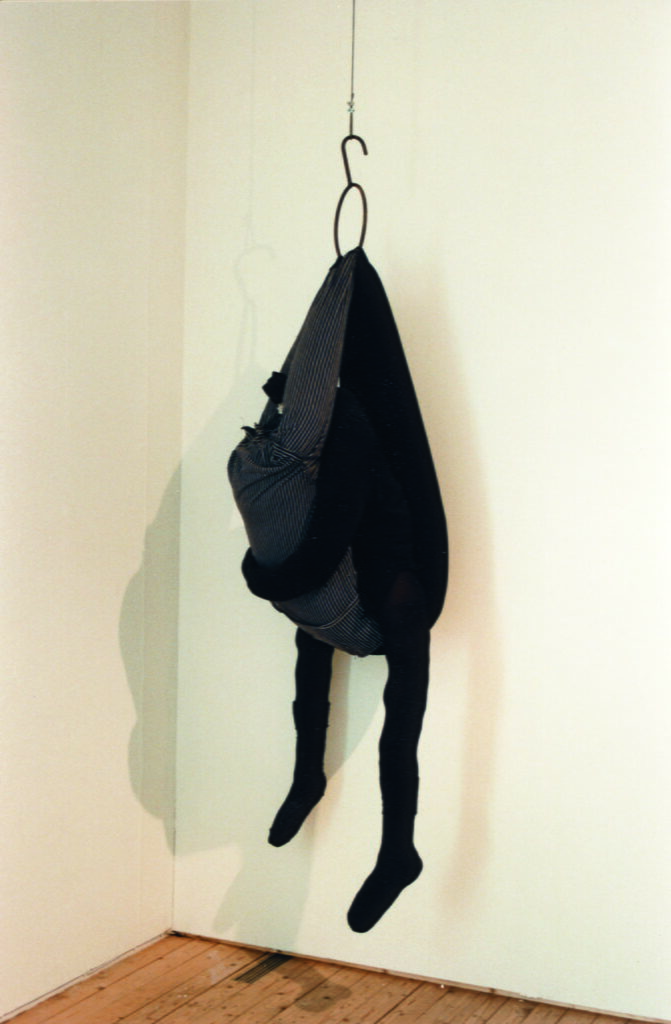 Ett verk av Louise Bourgeois, tyg hängandes i en krok. Från tyget hänger två fyllda stumpor ner.
