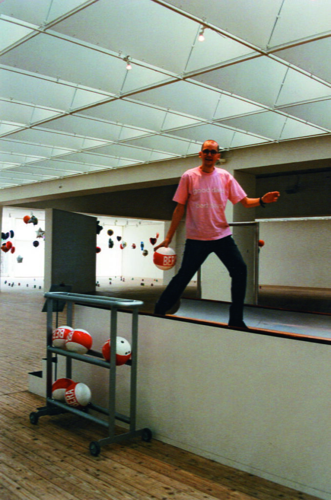 En man iklädd rosa tröja står på bowlingbanan och ska kasta iväg ett klot.