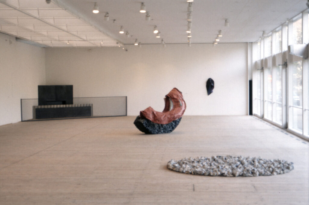 Flera skulpturer i organiska former och olika material står på golvet i konsthallen.