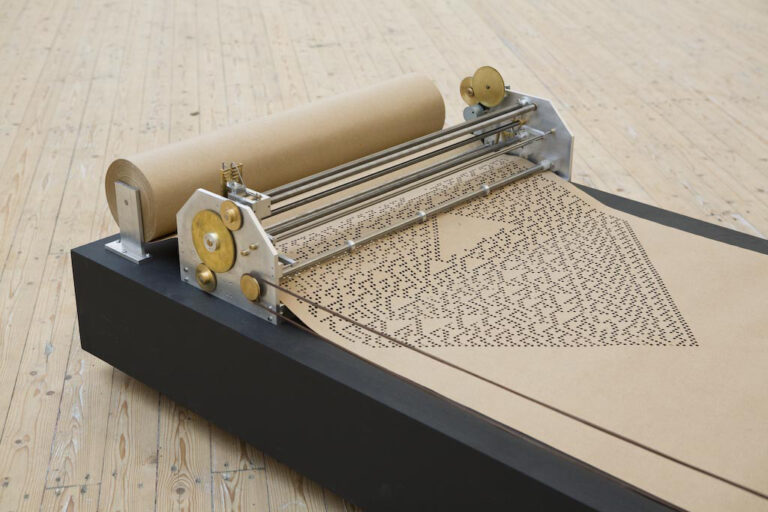 Elektrisk maskin gör ett vackert mönster av hål i ett brunt papper.