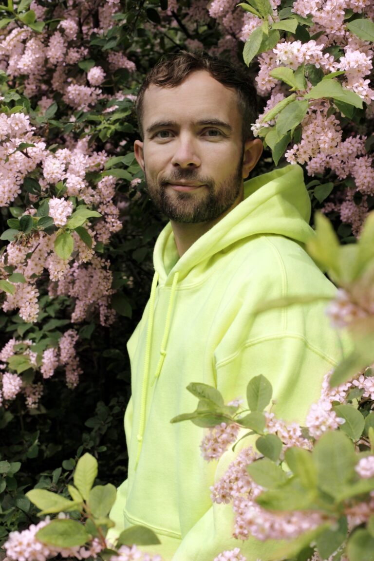 Porträtt av Olof Dreijer i rosa blommande buskage