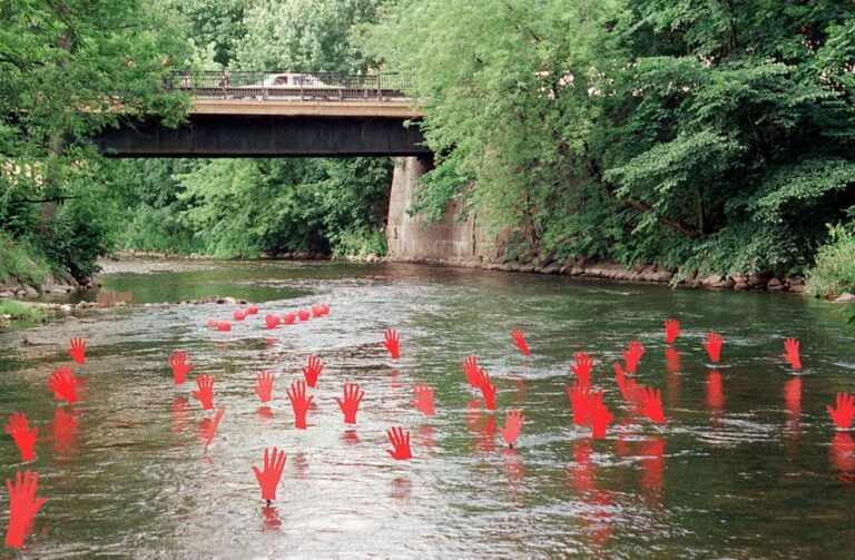 Vattenbryn där röda händer sticker upp över vattenytan