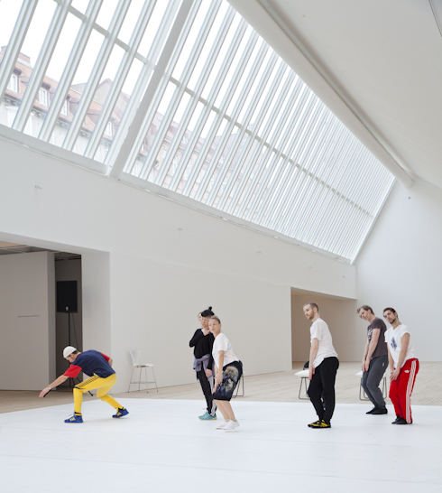 People performing choreographic movements in the art gallery's bright room.