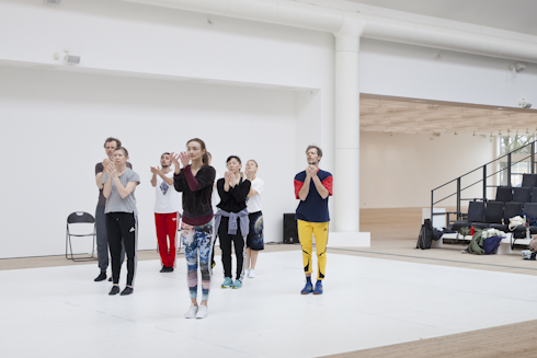 People performing choreographic movements in the art gallery's bright room.