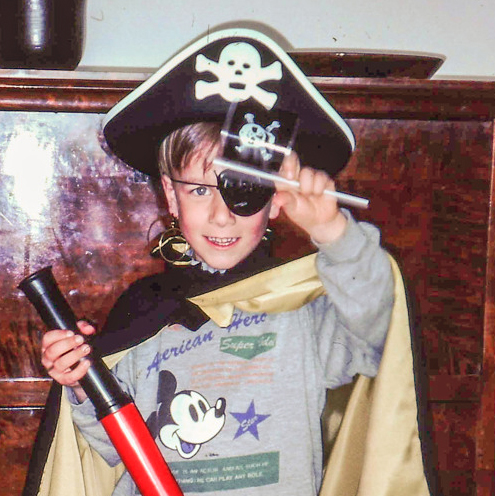 Barn utklädd till pirat framför en mörkbrun byrå