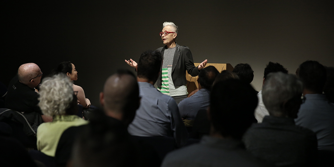 Barbara Hammer presenterar framför publik i svart rum