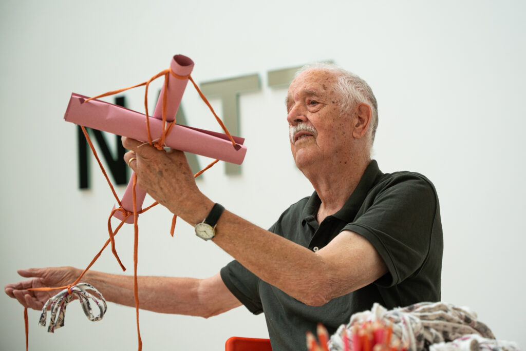 an elderly gentleman creates a work of art with textile and paper.