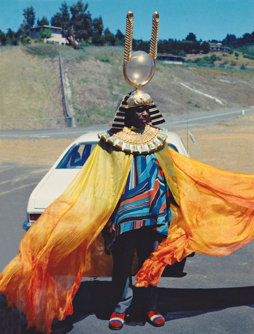 En man klädd inspirerad av egypten ståendes framför en bil utomhus