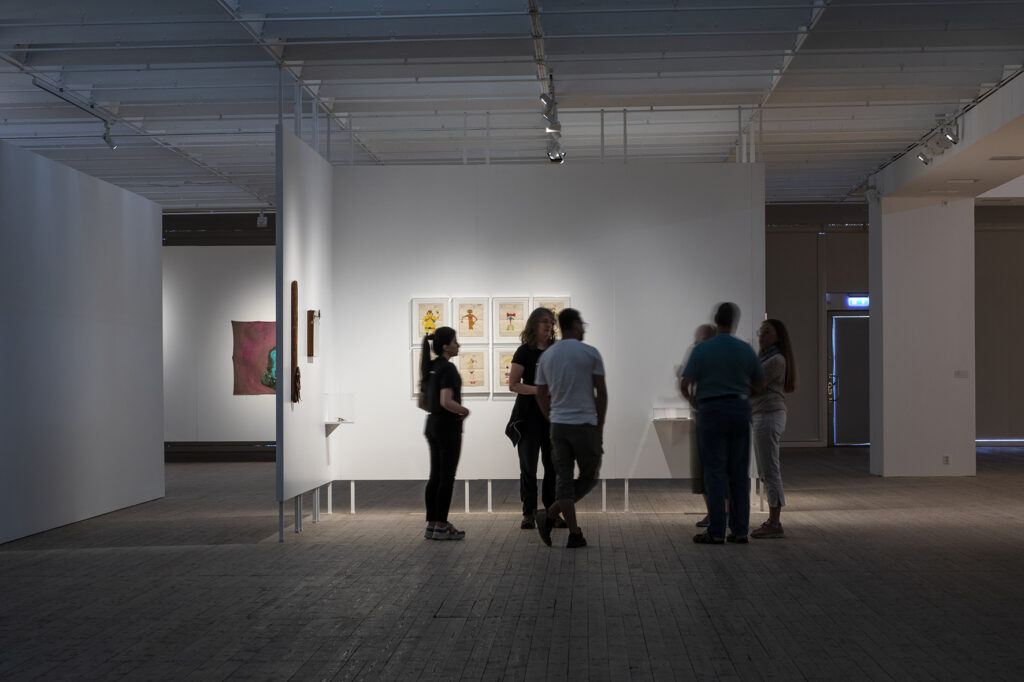 Group of people take part in a tour of Leonilson's dark showroom.