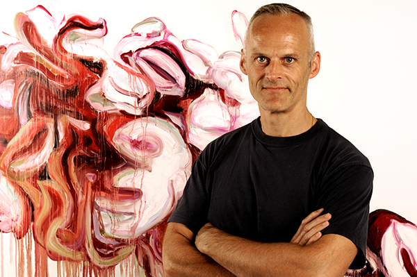 Bild av konstnären Martin Gustavsson framför en av sina kraftfulla målningar i rött och vitt.