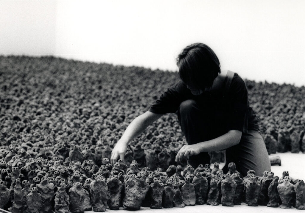 Installationsbild med en tekniker och hundratals små lerfigurer från utställning med Antony Gormley 1993.