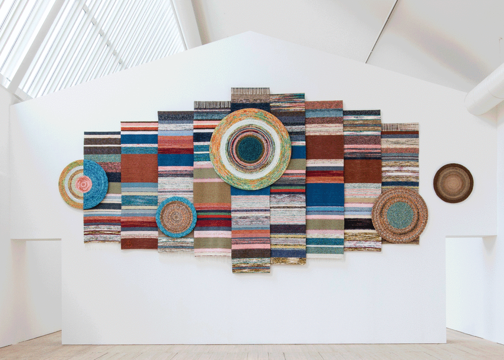 Ljusschaktet i konsthallens utställningsrum med Ann Böttchers färgrika verk gjort av mattrasor.