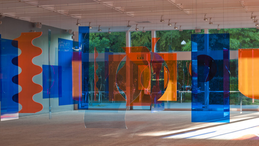 Färgstark installationsbild av ett hängande konstverk i orange och blått plexiglas, från Siri Aurdals utställning.