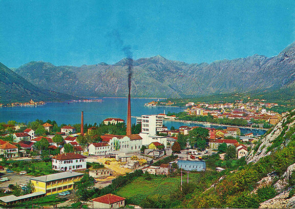 Gammalt vykort i klara färger, en vy över en by mellan bergen, kanske centraleuropa.