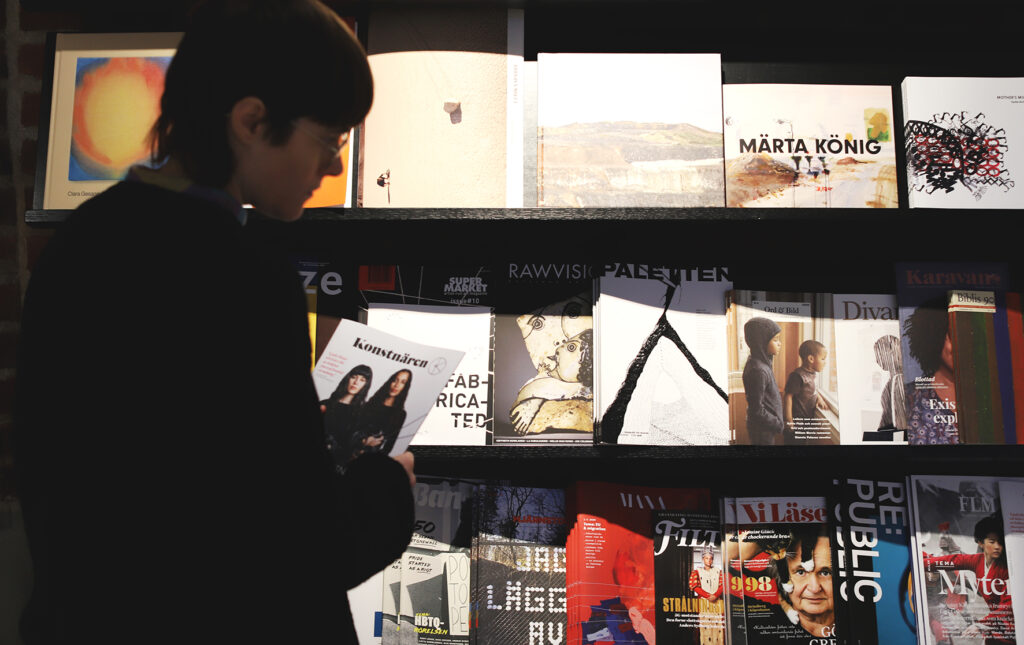 Ung kvinna tittar på olika tidningsmagasin i bokhandeln