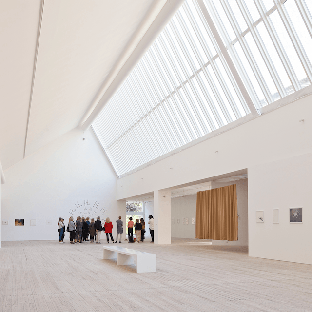 A group of people on a guided tour in the art gallery's stunning light shaft.