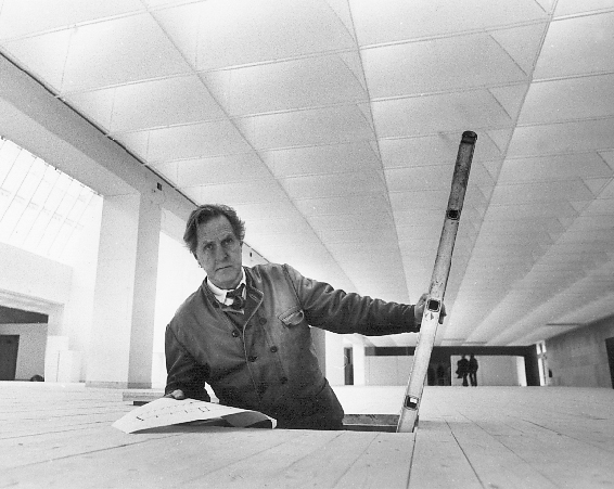Svartvit bild av arkitekten Klas Anselm som tittar upp ur en lucka i golvet på Malmö Konsthall.