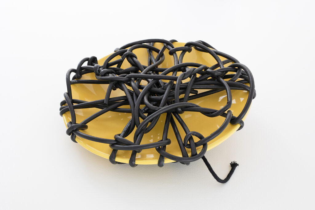 A yellow object resembling a gemstone wrapped in brown leather shoelaces.