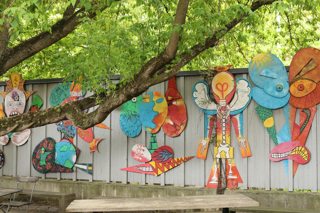 Färgglada figurer sitter på en vägg på konsthallens innergård