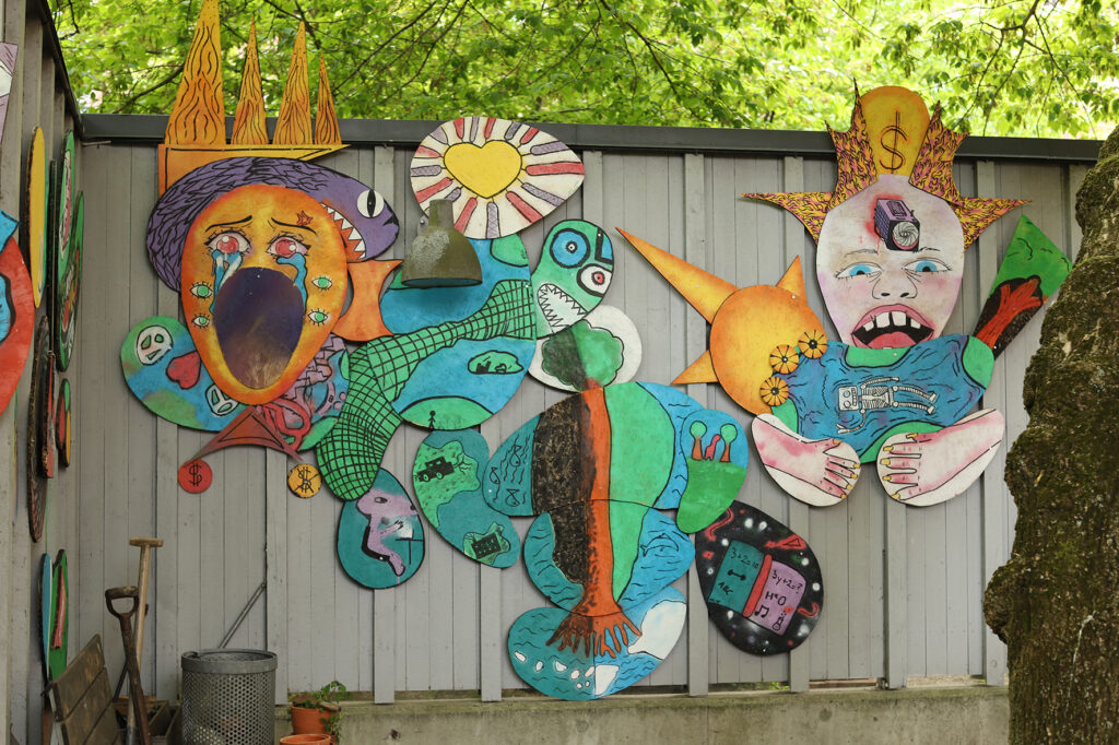 Färgglada figurer sitter på en vägg på konsthallens innergård