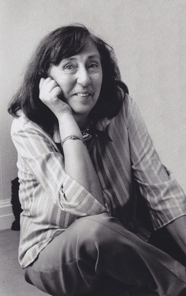 Black and white portrait of Inger Ekdahl, resting her chin on her hand and smiling.